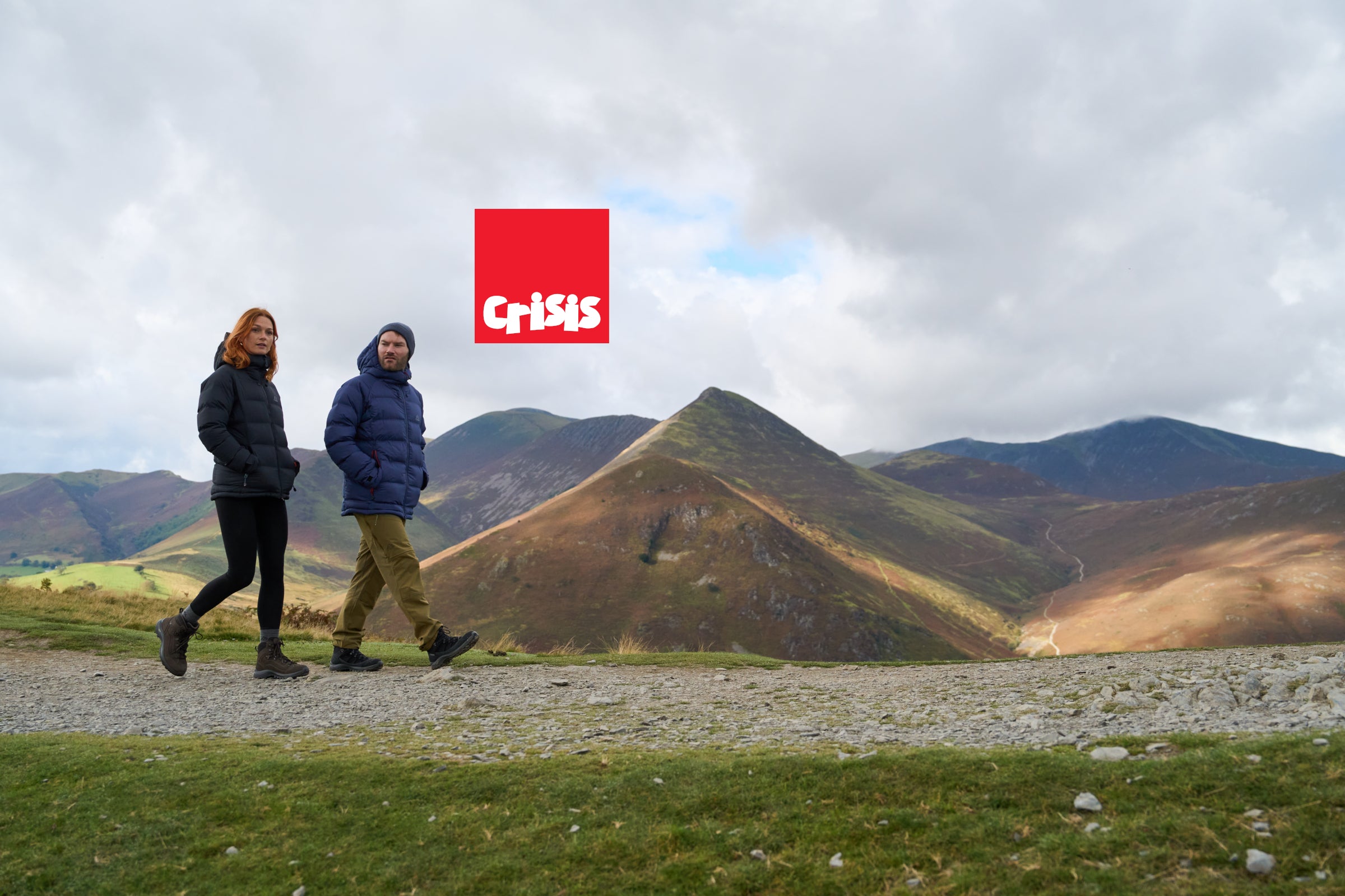 Hikers walking in the countryside with the Crisis logo placed over a mountain view