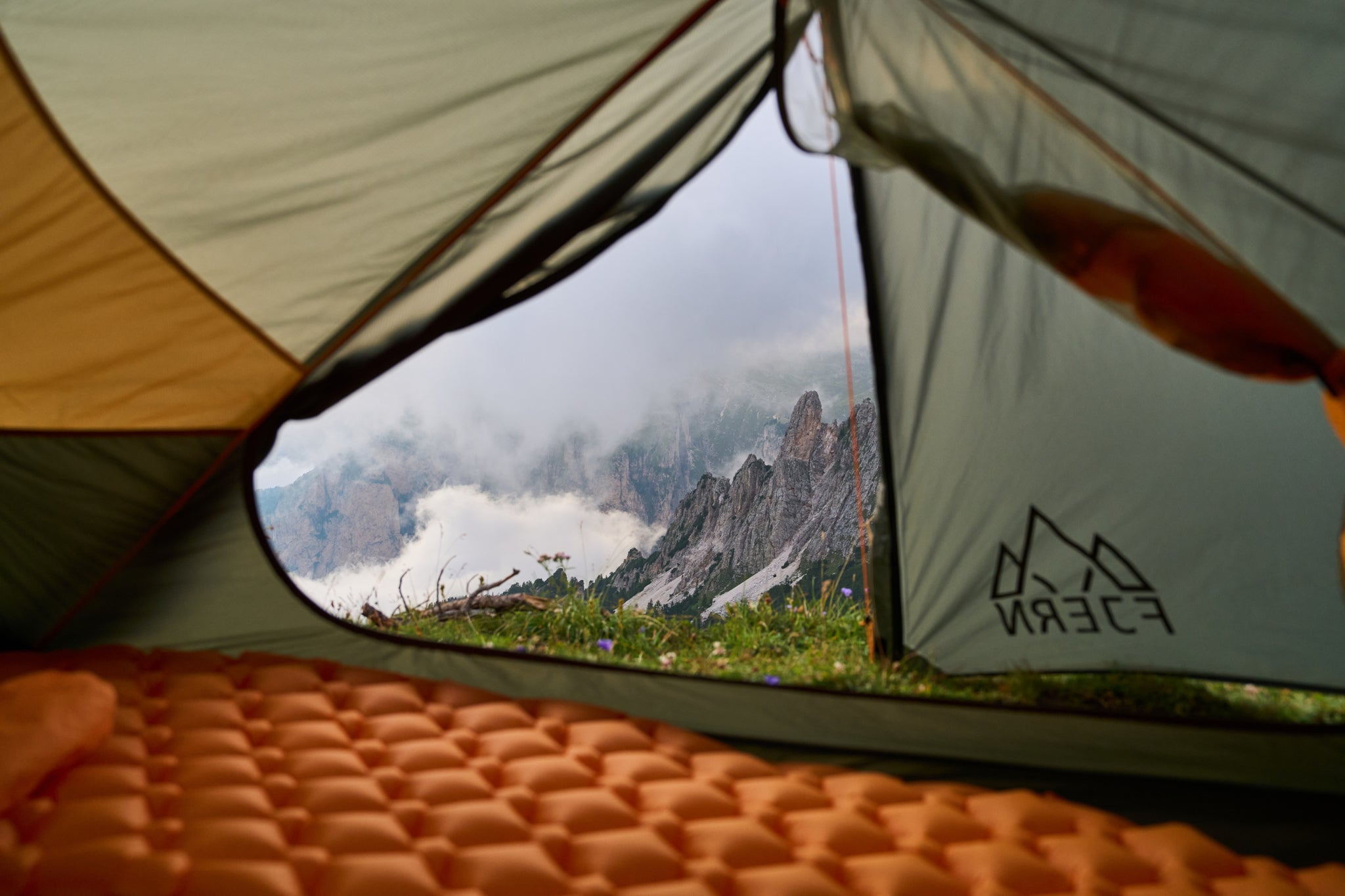 View from inside a Fjern tent, overlooking a cloudy mountain landscape