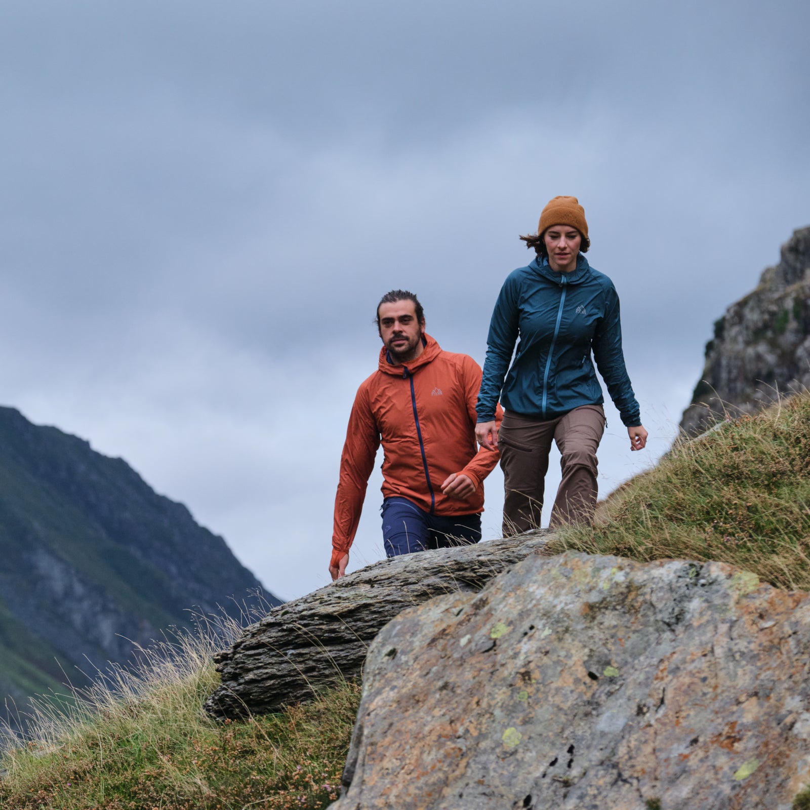 Two hikers wearing Fjern jackets trekking in a mountainous landscape