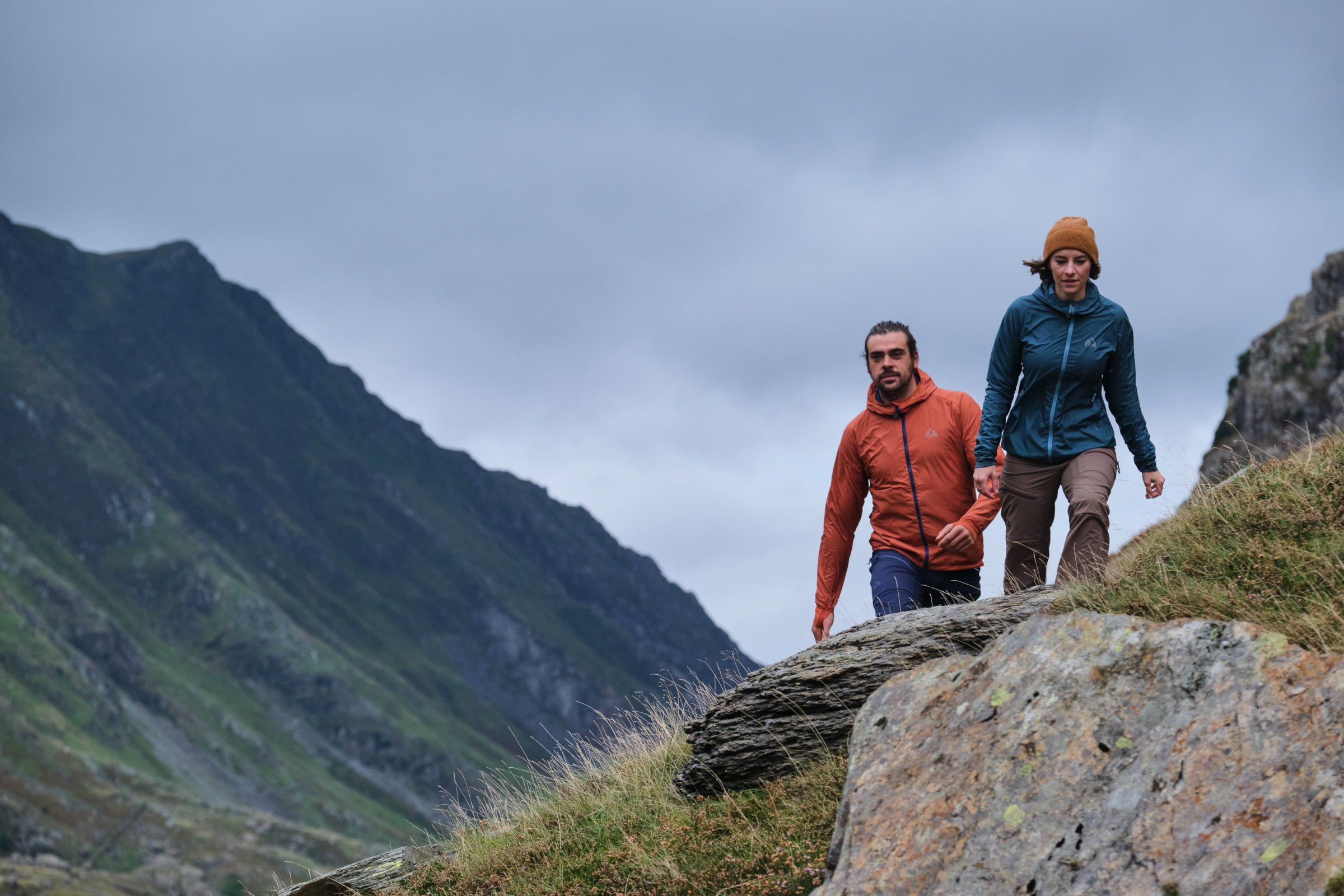 Two hikers wearing Fjern jackets trekking in a mountainous landscape