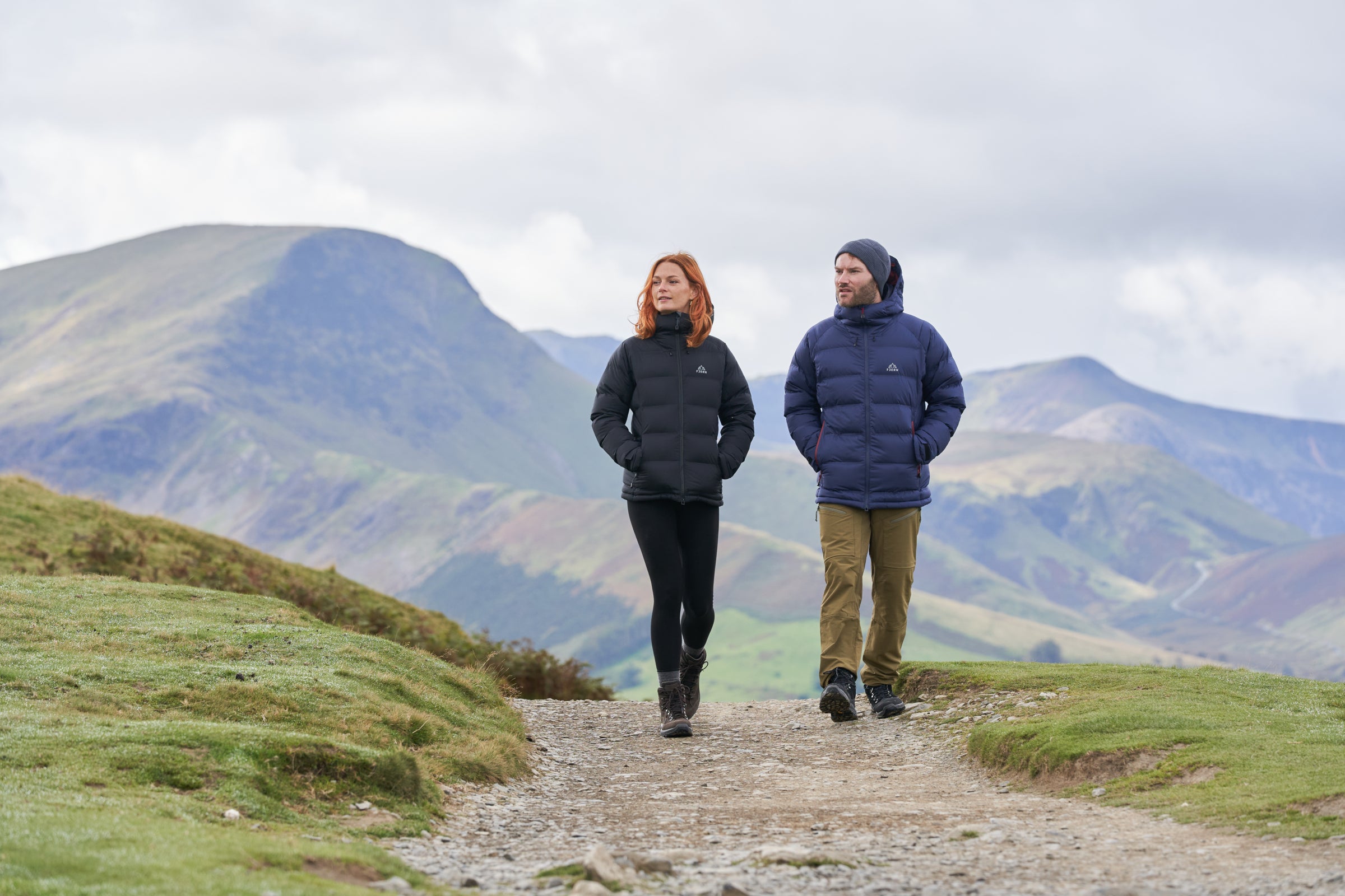 Two people walking on a trail in the mountains