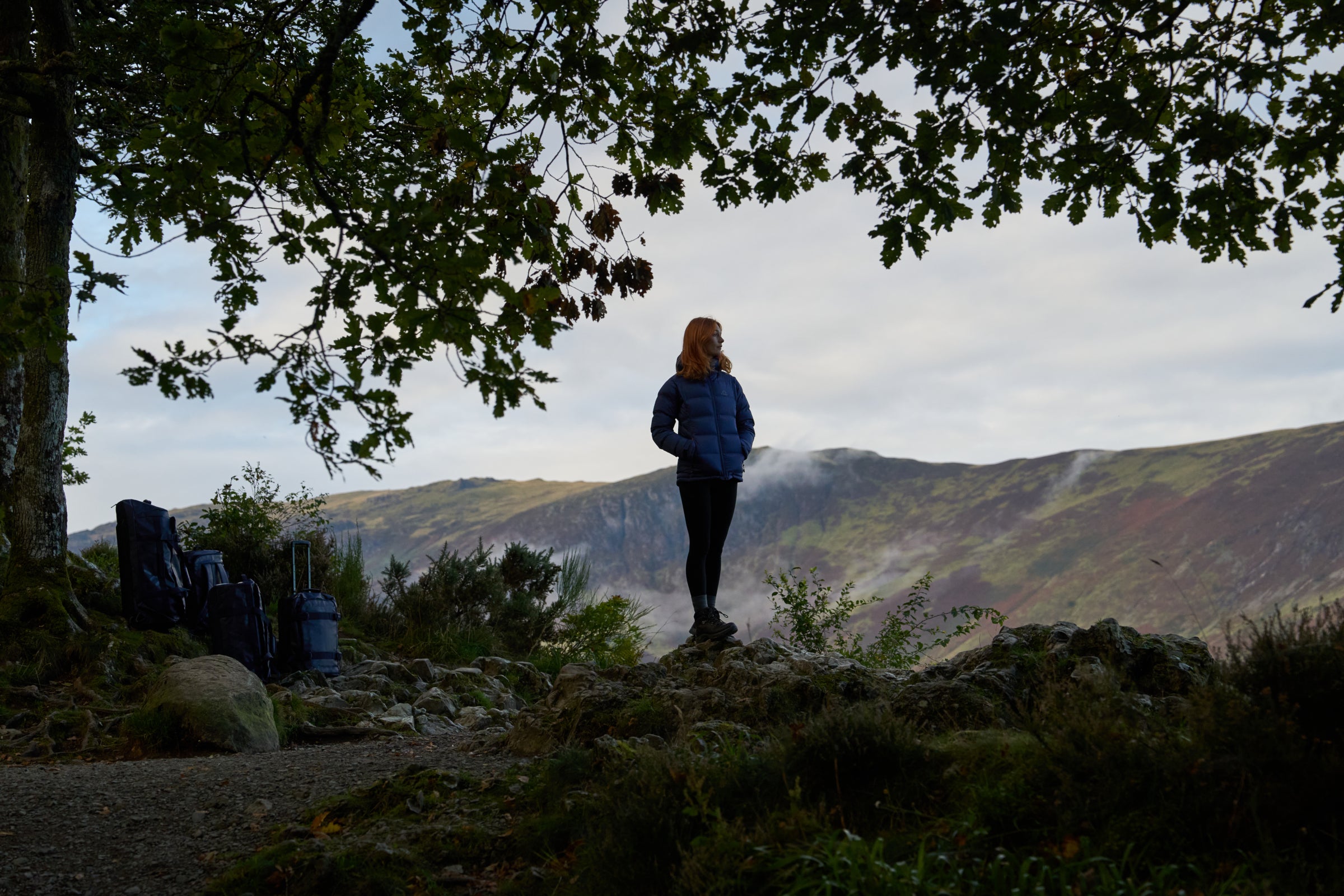 Person in a blue Aska jacket standing in a scenic outdoor location