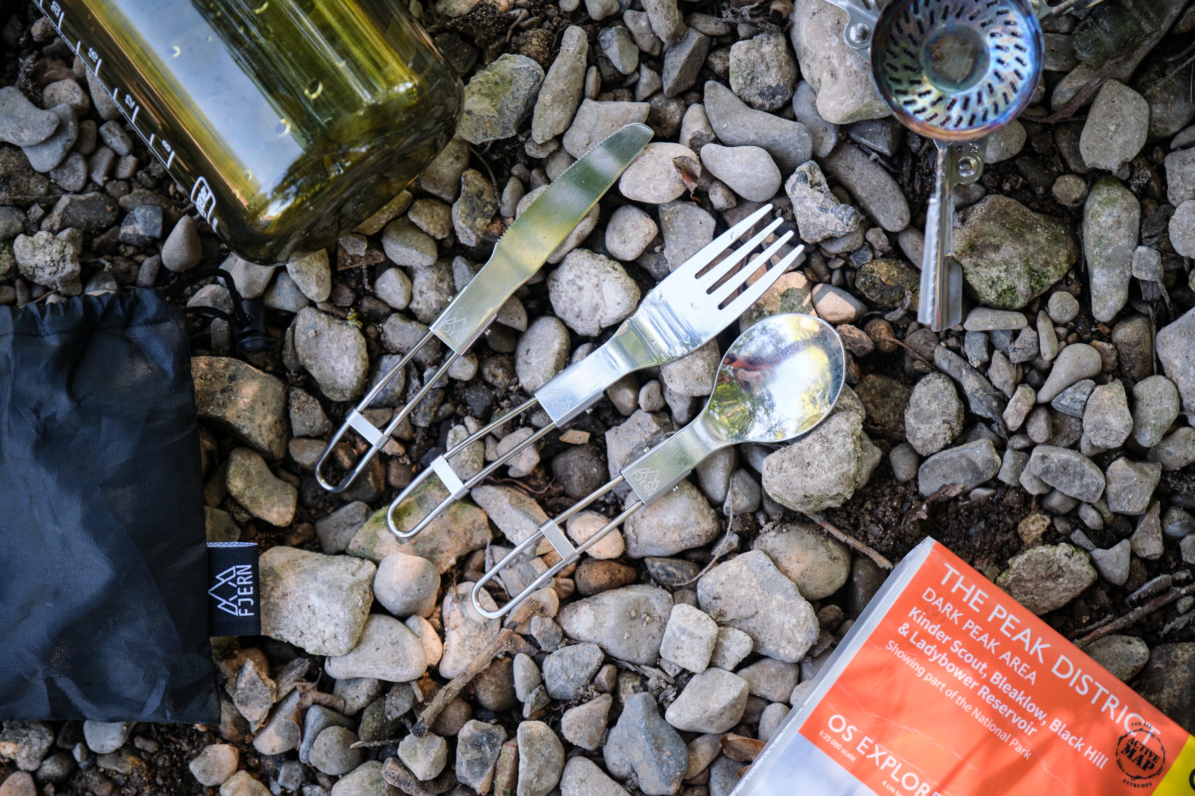 Fjern camping utensils, including a knife, fork, and spoon, placed on rocky ground