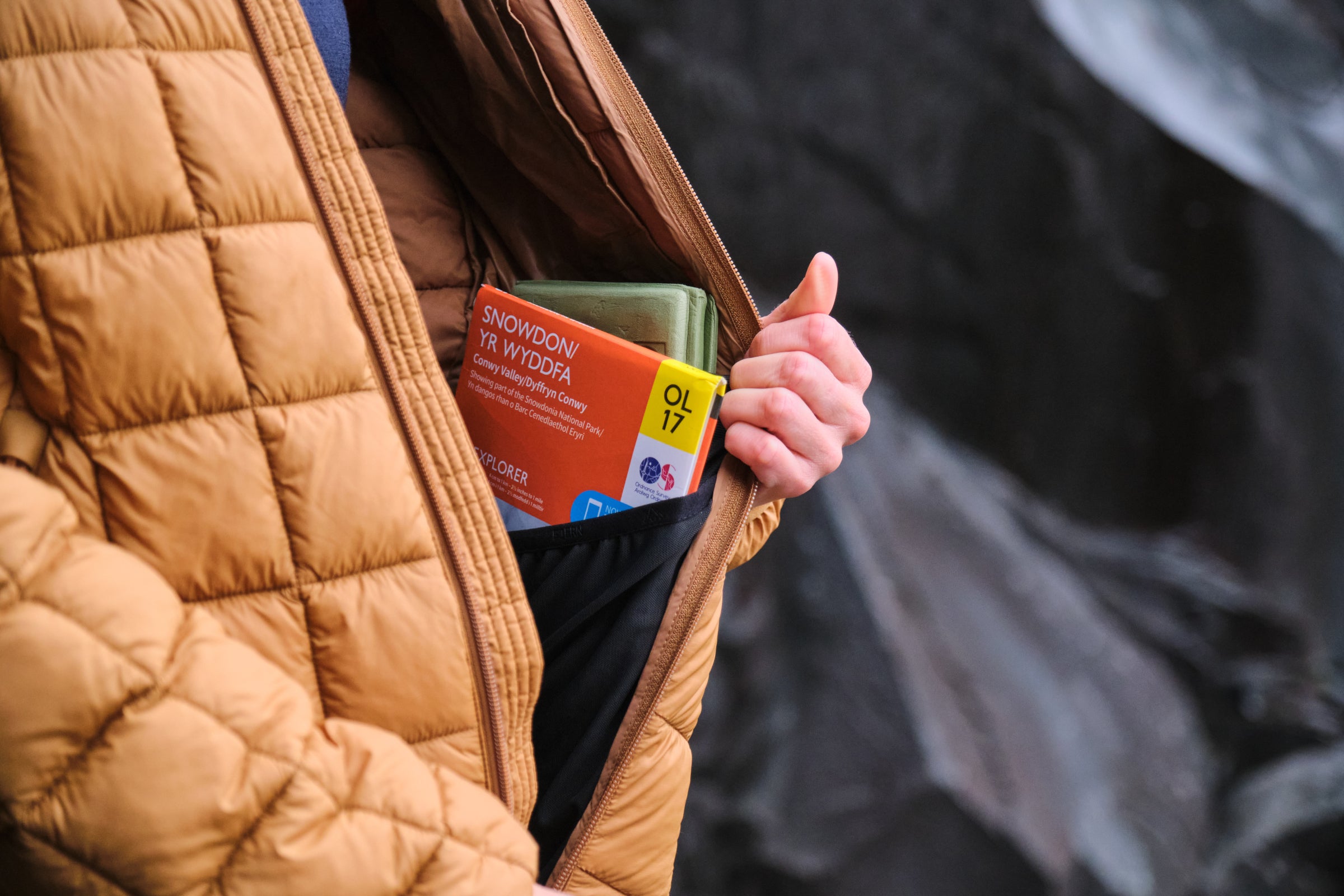 A person holding a map of Snowdon in the pocket of a Fjern jacket