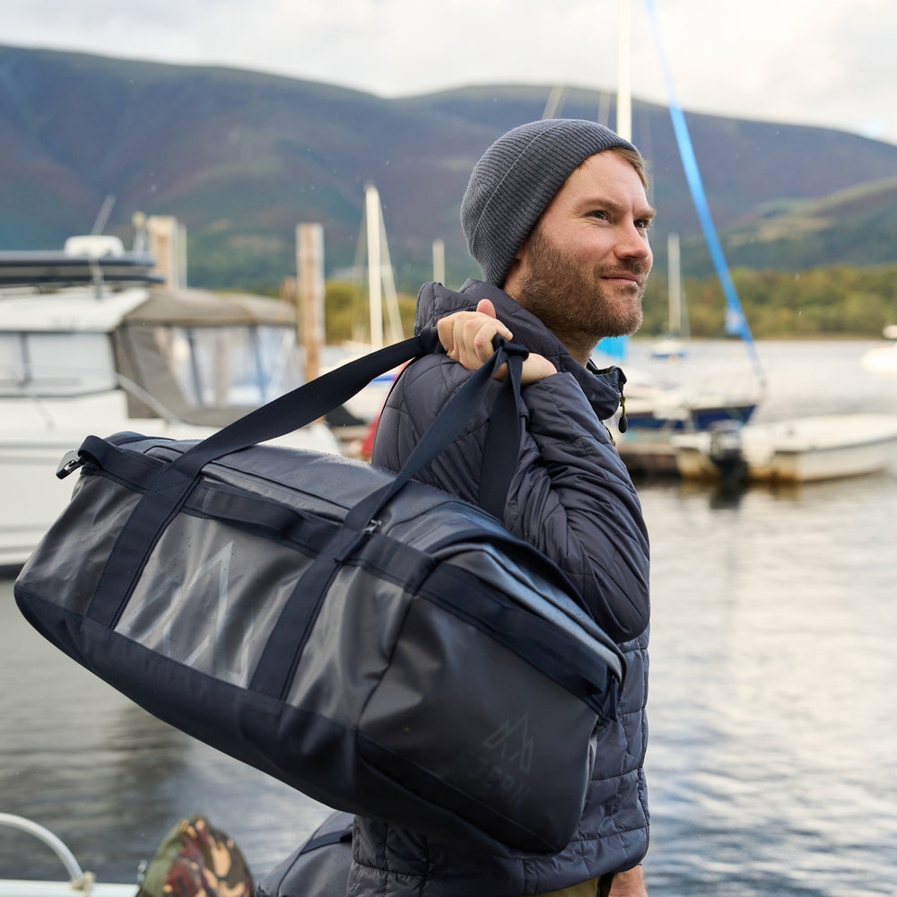 Fjern - Fördra 70L Duffle Bag (Midnight) | Made from durable 100% recycled polyester with a TPU-film laminate, the Fördra duffle bag offers 70L of storage, multiple pockets, and versatile carrying options