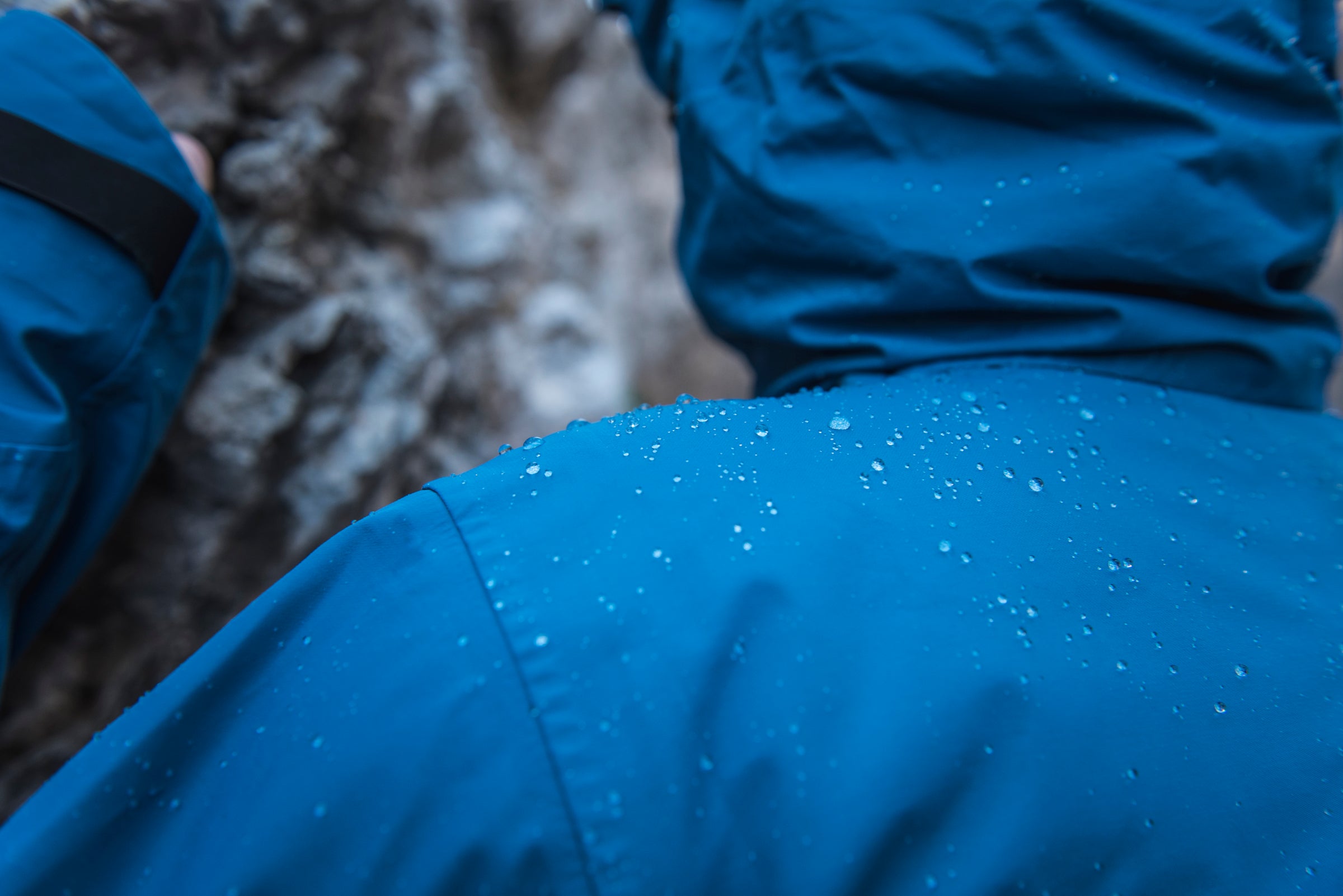 Close-up of a blue waterproof jacket with water droplets on the back